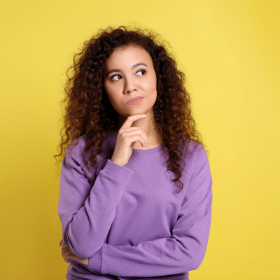 Woman with finger on chin, contemplating Invisalign® vs. Traditional Braces