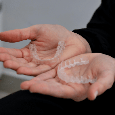 Person holding two halves of Invisalign aligners, representing Invisalign benefits