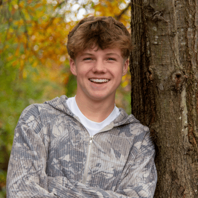 Teenage boy leaning against a tree, representing Invisalign treatment FAQs